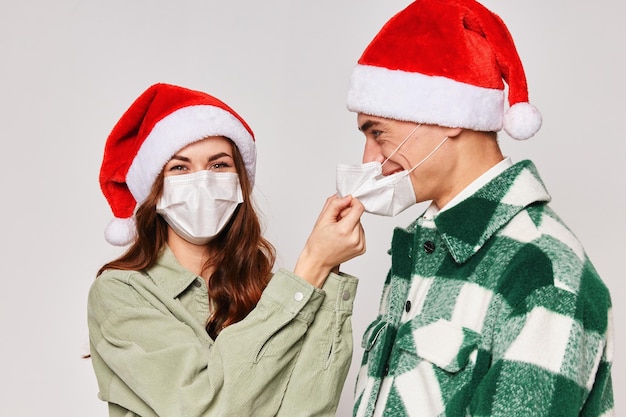 Casal jovem com chapéus de natal máscaras médicas closeup fundo cinza