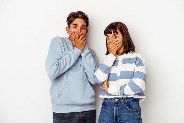 Casal jovem de raça mista isolado no fundo branco com medo e medo.