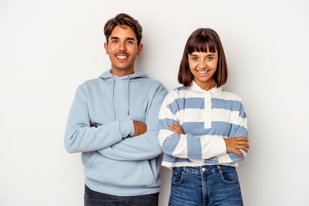 Casal jovem de raça mista isolado no fundo branco que se sente confiante, cruzando os braços com determinação.