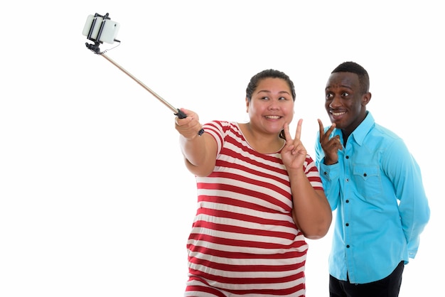 Casal jovem de raça mista usando bastão de selfie para tirar foto