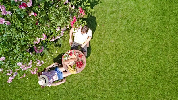 Casal jovem desfrutando de comida e bebida no lindo jardim de rosas em vista aérea de um encontro romântico