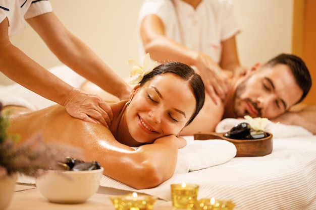 Casal jovem desfrutando de massagem nas costas no spa de saúde O foco está na mulher sorridente