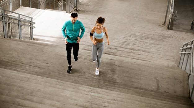 Casal jovem e bonito correndo no ambiente urbano