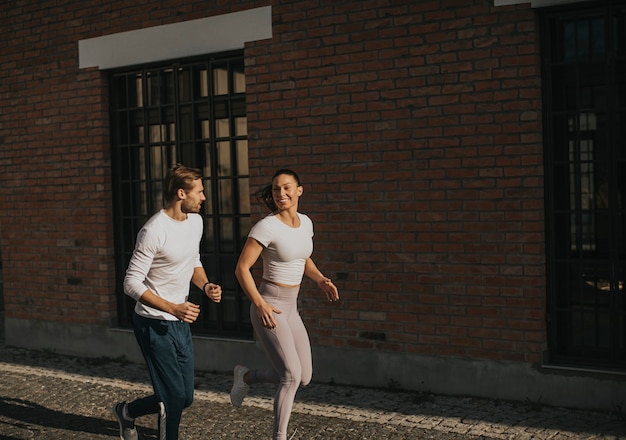 Casal jovem e bonito correndo no ambiente urbano