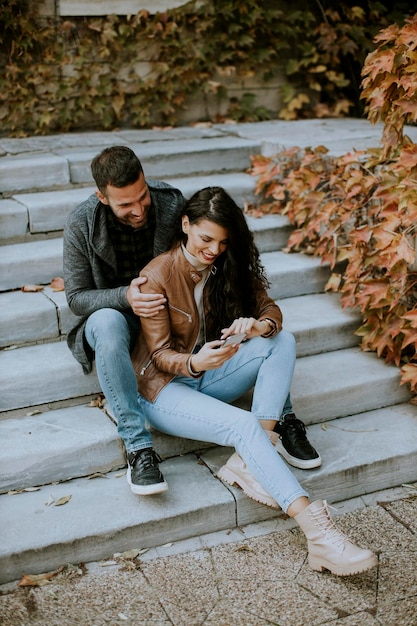 Casal jovem e bonito sentado em uma escada externa em um dia de outono