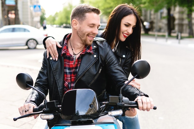 Casal jovem e elegante se divertindo enquanto andava de scooter elétrico na rua da cidade