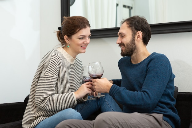 Casal jovem e feliz bebendo vinho e relaxando em casa