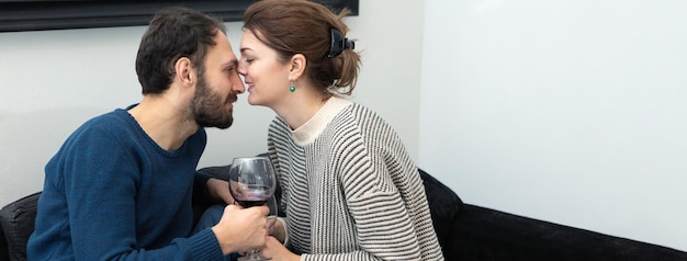 Casal jovem e feliz bebendo vinho e relaxando em casa