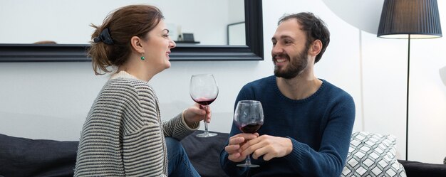 Casal jovem e feliz bebendo vinho e relaxando em casa