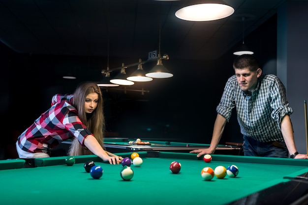 Casal jovem e lindo jogando bilhar em bar