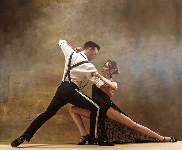 Casal jovem e moderno flexível dançando tango no estúdio. Retrato da moda de atraente casal dançando. Homem e mulher. Paixão. Ame. pele perfeita facial e maquiagem. Emoções humanas - amor e paixão