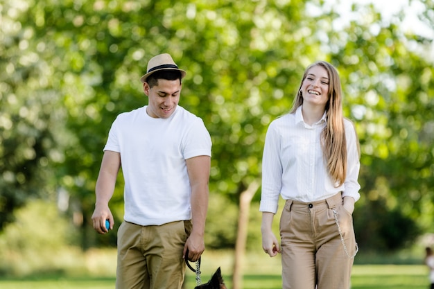 Casal jovem e moderno passeando e brincando com seu cachorro Border Collie em um parque