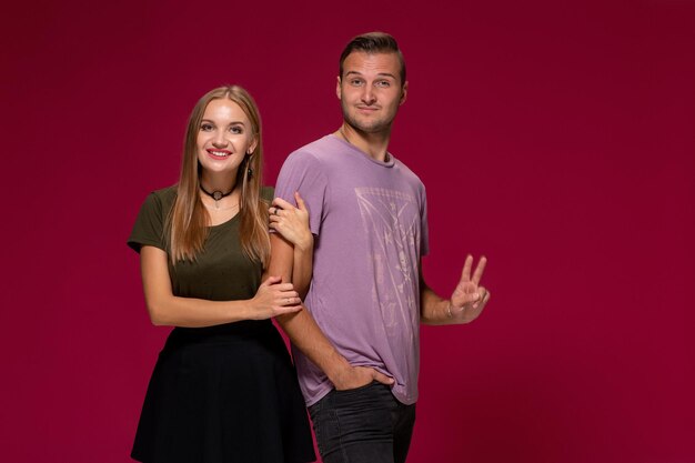 Casal jovem e simpático posando no estúdio, expressa emoções e gestos, sorrindo, sobre um fundo cor de vinho