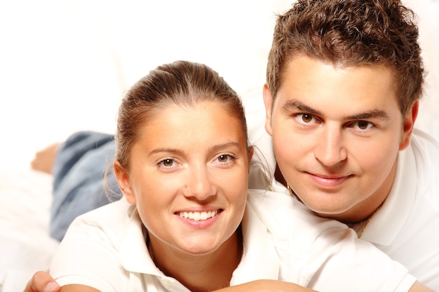 Casal jovem e simpático sorrindo e descansando em um sofá na sala de estar