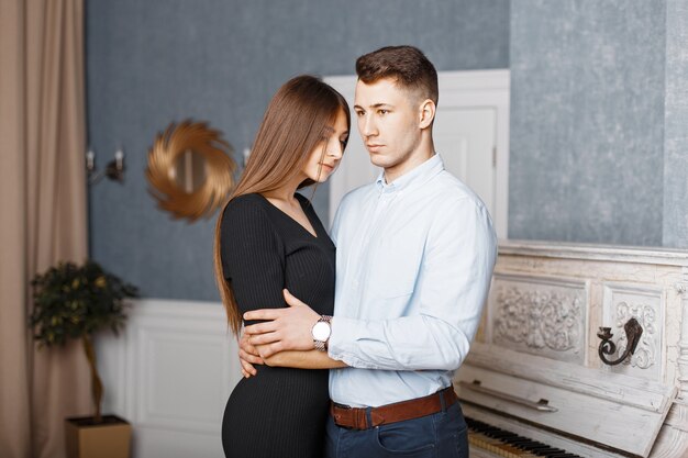 Casal jovem elegante com roupas retrô da moda perto de um piano vintage