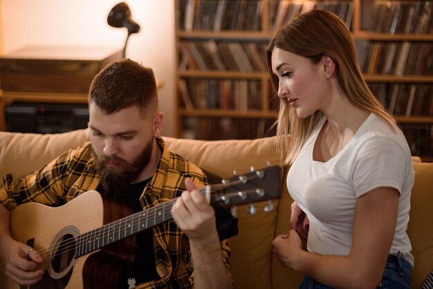 Casal jovem em casa tendo um encontro romântico enquanto toca guitarra