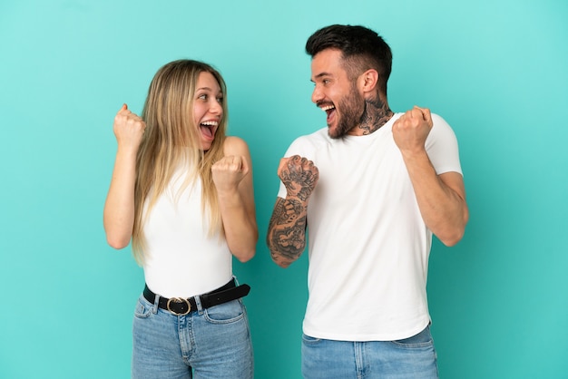 Casal jovem em fundo azul isolado comemorando vitória