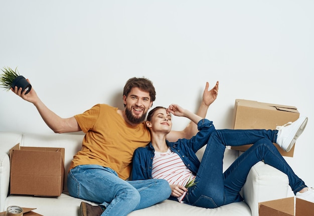 Casal jovem em um novo apartamento em caixas de sofá branco com coisas se movendo