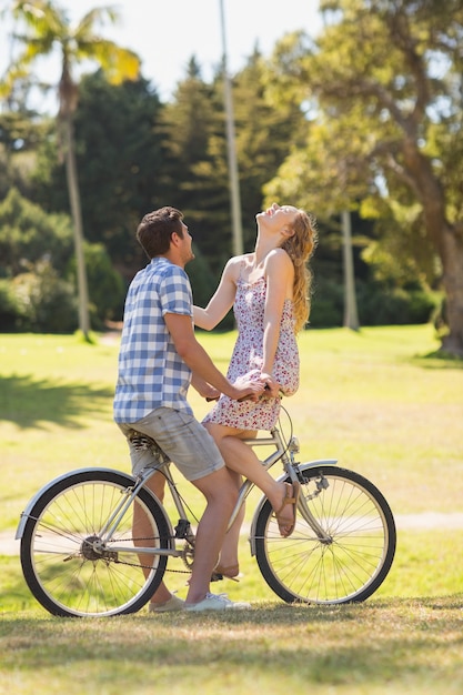 Foto casal jovem em um passeio de bicicleta no parque