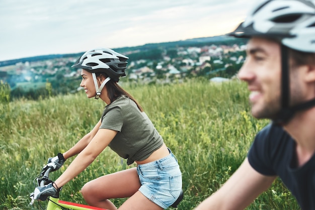 Casal jovem está andando de bicicleta em fatbikes e capacetes de perto