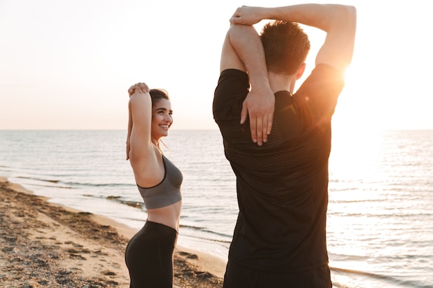 Casal jovem esticando as mãos enquanto faz exercícios