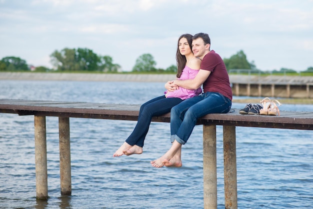 Casal jovem feliz andando no cais no lago em um dia ensolarado de verão