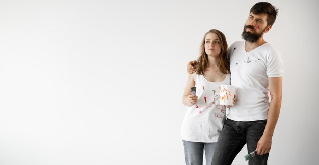 Foto casal jovem feliz apaixonado em camisetas brancas faz reformas atualizando a pintura das paredes se preparando para mudar para uma nova casa foco seletivo baner