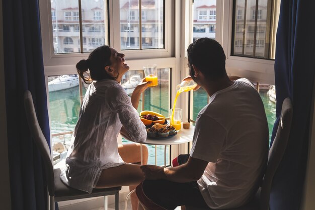 Casal jovem feliz, aproveitando o café da manhã no terraço