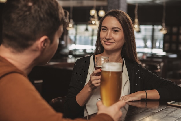 Casal jovem feliz, bebendo cerveja em um encontro no bar