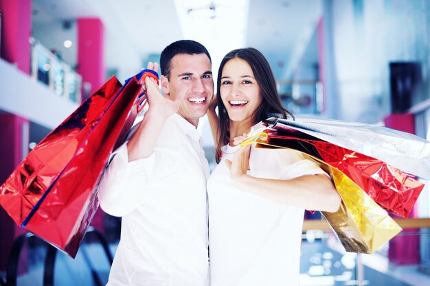 casal jovem feliz com sacos no shopping center