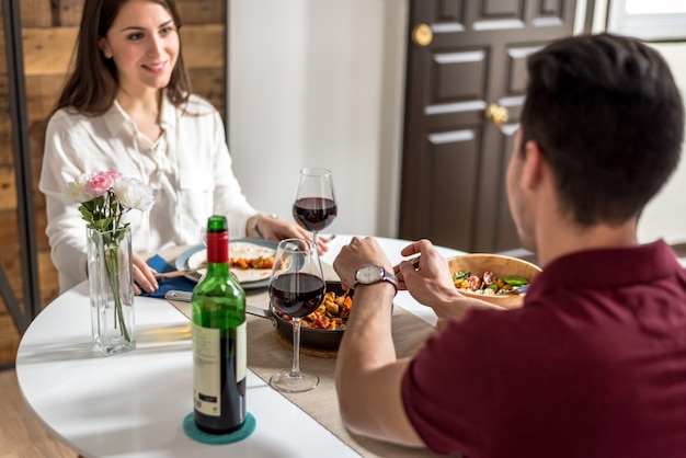 Foto casal jovem feliz comendo e bebendo vinho em casa