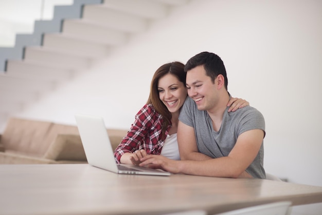 casal jovem feliz comprando on-line usando laptop, computador e cartão de crédito em sua casa de luxo