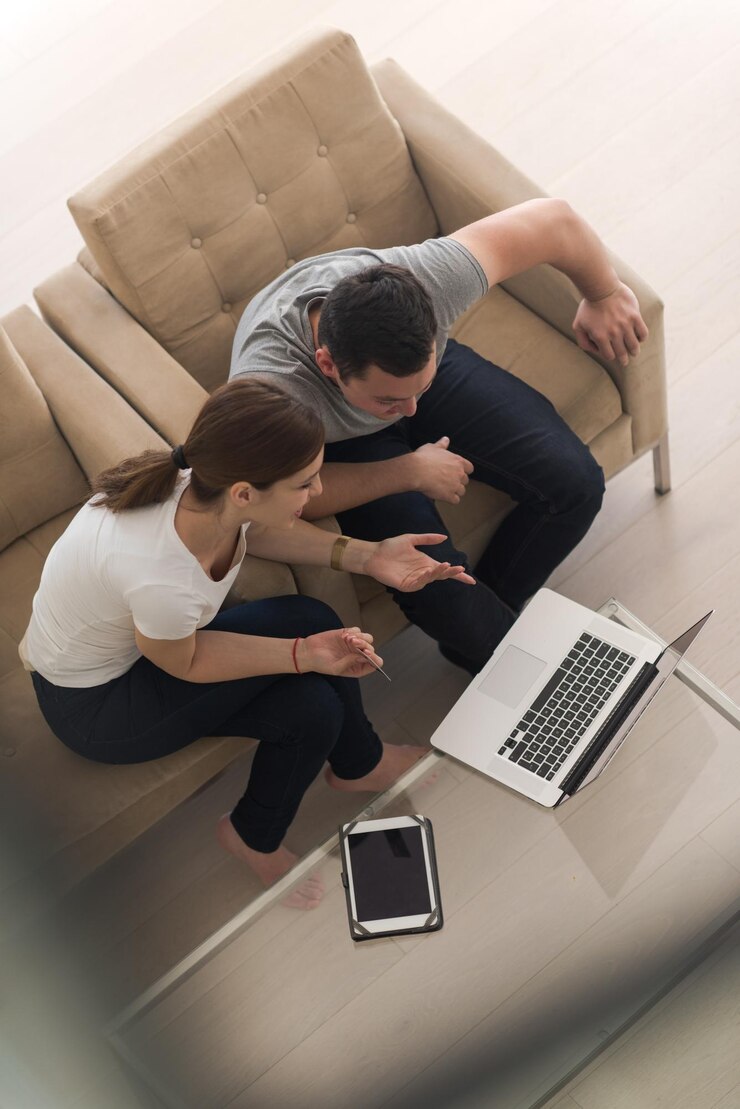 Foto casal jovem feliz comprando on-line usando laptop, computador e cartão de crédito em sua casa de luxo