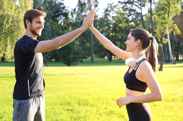 Casal jovem feliz dando mais cinco em pé no parque.