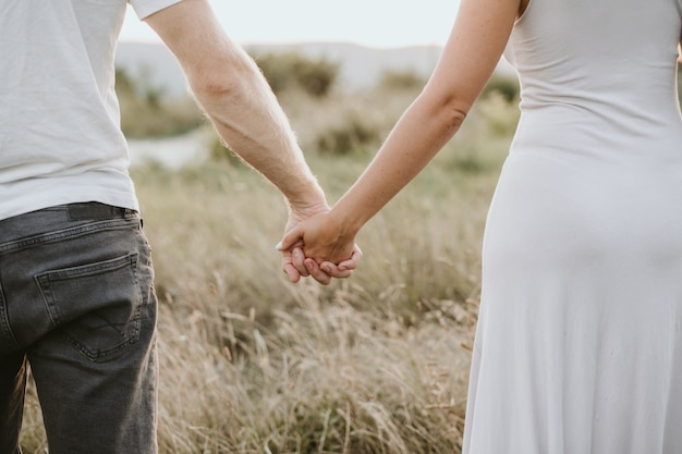 Casal jovem feliz de mãos dadas no fundo da natureza. conceito de amor