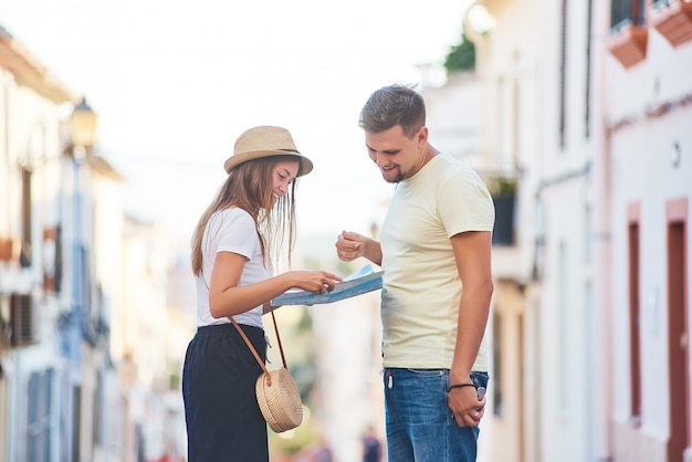 Foto casal jovem feliz de viajantes segurando o mapa nas mãos