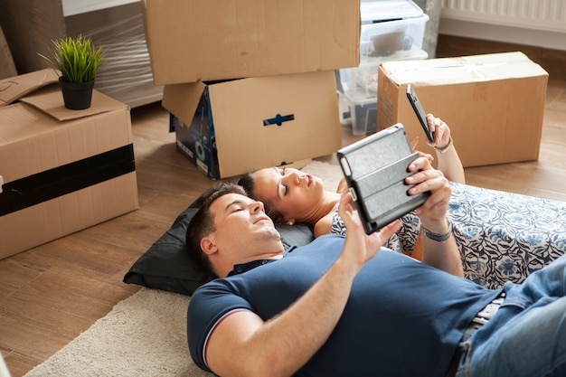 Casal jovem feliz deitado no chão perto de mover caixas. Família jovem se mudando para a nova casa.