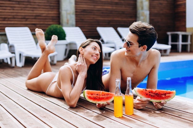 Casal jovem feliz, descansando perto da piscina no resort