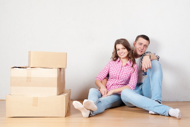 Casal jovem feliz desembalar ou caixas de embalagem e movendo-se para uma nova casa.
