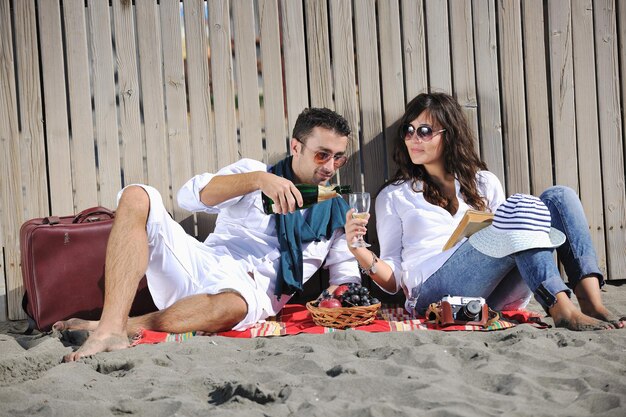 casal jovem feliz desfrutando de piquenique na praia e se divertir nas férias de verão