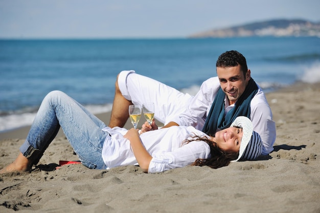 casal jovem feliz desfrutando de piquenique na praia e se divertir nas férias de verão