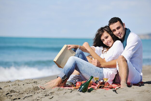 casal jovem feliz desfrutando de piquenique na praia e se divertir nas férias de verão