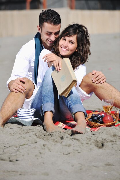 casal jovem feliz desfrutando de piquenique na praia e se divertir nas férias de verão