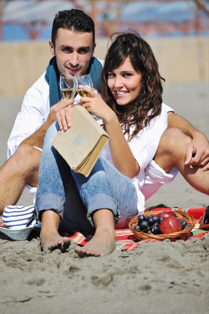 casal jovem feliz desfrutando de piquenique na praia e se divertir nas férias de verão