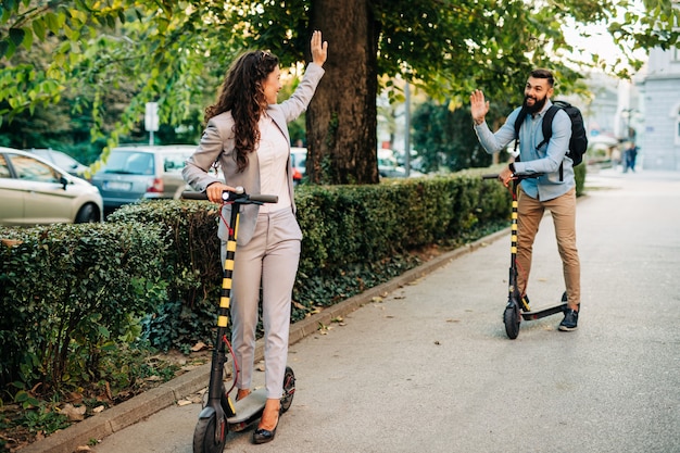 Casal jovem feliz desfrutando juntos enquanto andava de scooters elétricos no parque da cidade.