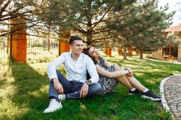 Casal jovem, feliz e amoroso, sentados juntos na grama do parque e curtindo um ao outro