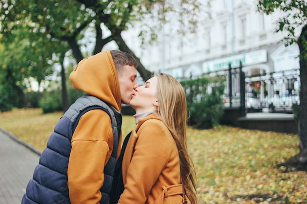 Casal jovem feliz em amigos de adolescentes amor vestidos em estilo casual beijando na rua cidade outono