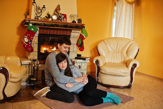 Casal jovem feliz em casa por uma lareira na sala de estar quente em dia de inverno