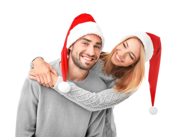 Casal jovem feliz em chapéus de Papai Noel em fundo branco. Conceito de natal