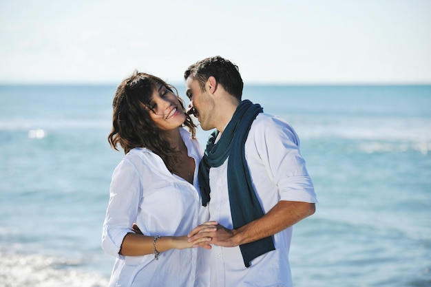 casal jovem feliz em roupas brancas tem recreação romântica e diversão na bela praia de férias